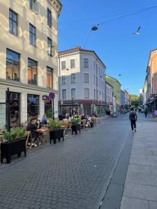 a city street with people sitting at tables and buildings at Cozy Studio - 9 min Walk from Oslo Central Station in Oslo