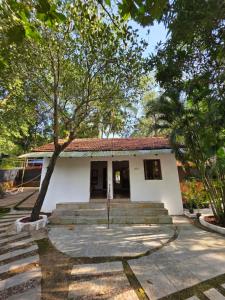 a small white building with stairs and trees at Joe Banana Stays in Anjuna