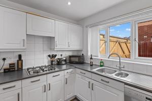 a kitchen with white cabinets and a sink and a window at Ideal Budget Contractor Stay - 4B Home w en-suites in Great Sankey