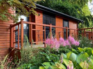 a cabin with a deck and flowers in front of it at The Hermitage in Penrith