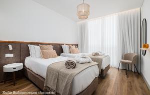a bedroom with two beds and a chair at Mónaco Suites & Garden in Ponta Delgada