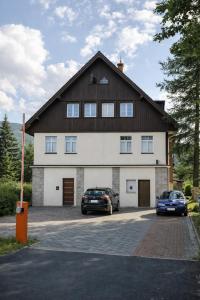 a large house with two cars parked in a parking lot at Wonderful Dream Apartament z widokiem na Śnieżkę in Karpacz