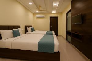 a bedroom with two beds and a flat screen tv at Olive Hotel in Hyderabad