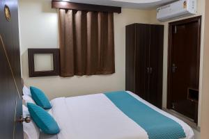 a bedroom with a bed with blue pillows and a window at Olive Hotel in Hyderabad