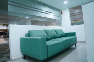 a green couch in a room with a wall at Olive Hotel in Hyderabad