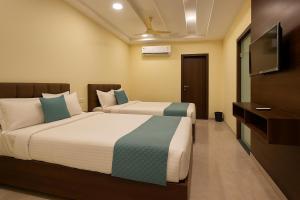 two beds in a hotel room with a television at Olive Hotel in Hyderabad