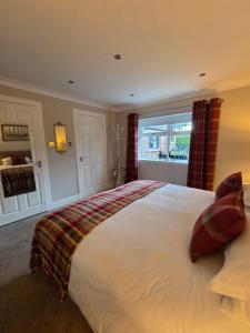 a bedroom with a large white bed and a window at The Cairn at North Lodge, Rural Guest Suite in Kirriemuir
