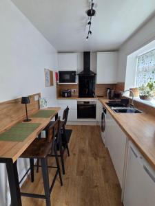 a kitchen with white cabinets and a wooden table with chairs at The Cairn at North Lodge, Rural Guest Suite in Kirriemuir