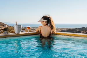 a woman sitting in a swimming pool with a glass of wine at Naxos Aethereal View in Kastraki +63 photos