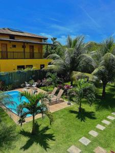 a resort with a pool and palm trees and a building at Vila Itacimirim in Itacimirim
