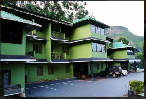 a green building with a parking lot in front of it at Nature Quite in Vattavada