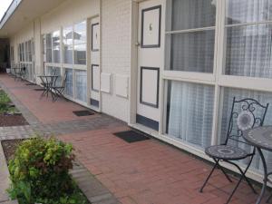 a patio with tables and chairs next to a building at Darlot Motor Inn in Horsham