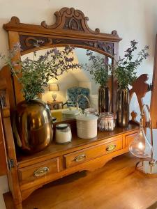 a wooden dresser with a mirror and vases on it at Room 3, Wedale House in Stow