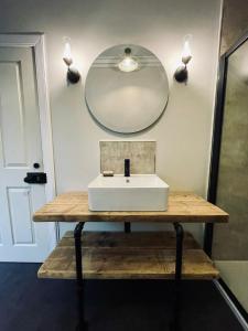 a white sink on a wooden table with a mirror at Room 3, Wedale House in Stow