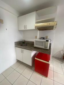 a small kitchen with a microwave on a counter at Silva Hospedagem AMERICAN FLAT BEIRA MAR apartamento por temporada in São Luís