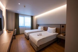a hotel room with two beds and a television at Reiwa Business Hotel in Osmaniye
