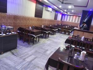 a restaurant with tables and chairs and a person in a room at Hotel Sagar in Agra