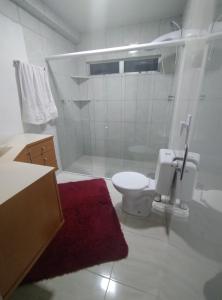 a white bathroom with a toilet and a shower at Ap bom descanso in Palhoça