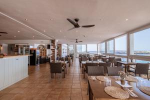 a restaurant with tables and chairs and a ceiling fan at Apartamentos Blancala in Cala Blanca