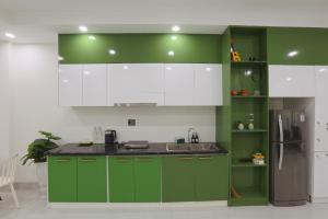 a kitchen with green and white cabinets and a refrigerator at Trà Homestay in Thôn Lại Thê +4 photos