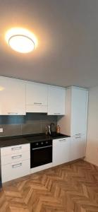 a kitchen with white cabinets and a black dishwasher at Central Living Brugg - Redapartment in Brugg