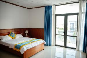a bedroom with a bed and a large window at An Hotel in Xóm Vĩnh Thanh