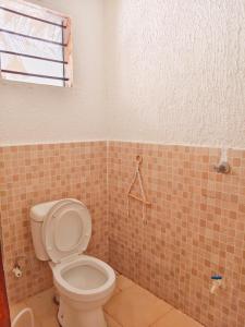 a bathroom with a toilet and a tiled wall at Sawa Sawa Beach Hotel&Backpacks in Malindi