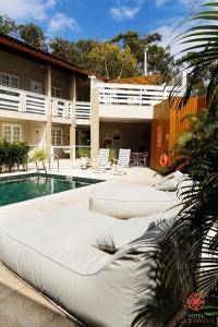 a swimming pool with a white couch next to a building at Hotel Geranius Ingleses in Florianópolis
