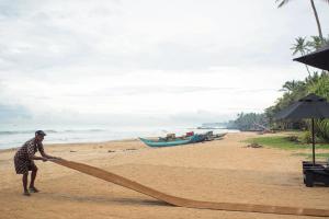 a man holding a large net on a beach at Arabella on Boossa in Galle