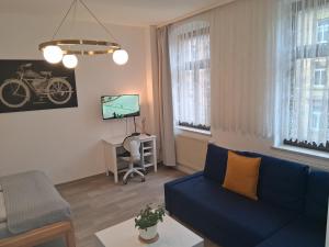 a living room with a blue couch and a desk at Geräumige Stadtwohnung mit Balkon in Zwickau