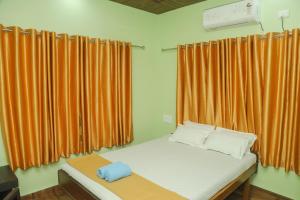 a bed in a room with orange curtains at Ambadnya Homestays in Dāhānu +72 photos