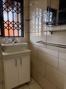 a white bathroom with a sink and a window at Amira Boutique Villa in Empangeni