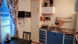 a kitchen with blue cabinets and a table and a window at Stuga Sandhem in Sandhem