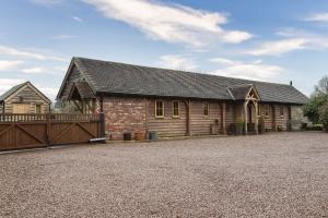 a large wooden house with a gate and a fence at Long Barn in Ludlow