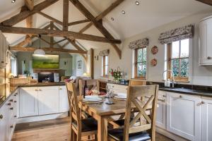 a kitchen with white cabinets and a wooden table with chairs at Long Barn in Ludlow