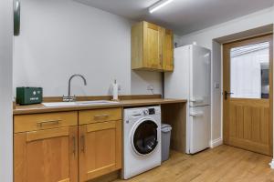 a kitchen with a washing machine and a refrigerator at Hill Top Farm in Penrith