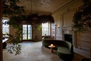 a living room with a green couch and a fireplace at Denton Hall in Ilkley