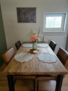 a wooden table with chairs and a vase of flowers on it at Whispering O - B&B Ermelo Speuld On the Veluwe in Ermelo +24 photos