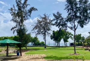 a green umbrella in a park with trees at Coral Waves Inn - Pasikuda in Kalkudah