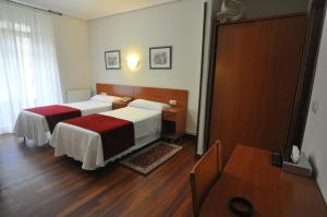 a hotel room with two beds and a table at Pension Alameda in San Sebastián