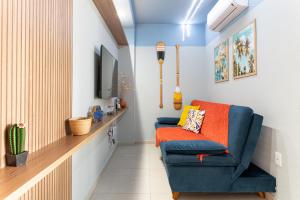 a living room with a blue chair and a television at Flat Coqueiros 101 Praia in Tamandaré
