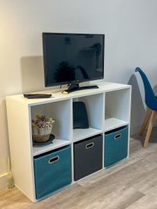 a white entertainment center with blue drawers and a tv at Casa Rosa in Parede