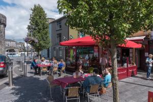 a group of people sitting at tables with red umbrellas at Shannon View Jungle House in Athlone