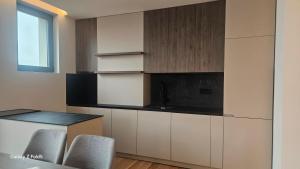 a kitchen with white cabinets and a counter with chairs at Zemun Golax Apartments in Belgrade