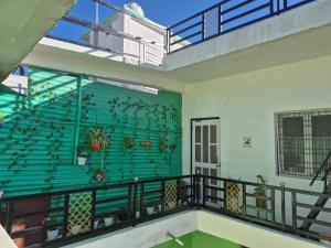 a balcony with a green wall with birds on it at Roaming Rovers - Pet-Friendly & Peaceful Homestay in Almora in Almora