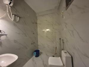 a white bathroom with a toilet and a sink at Roaming Rovers - Pet-Friendly & Peaceful Homestay in Almora in Almora +8 photos