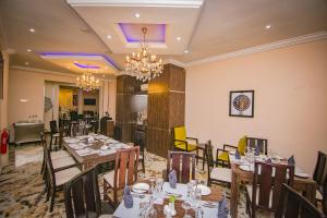 a dining room with tables and chairs and a chandelier at Joygate Hotels & Suites in Lagos