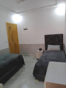 a bedroom with two beds and a door in a room at Chez Franck in Saïdia