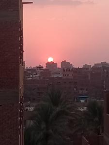 a sunset over a city with buildings and palm trees at Al Sawy Station in Cairo