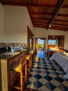 a kitchen with a checkered floor and a bedroom at Chalés Mirante da Colina in Venda Nova do Imigrante